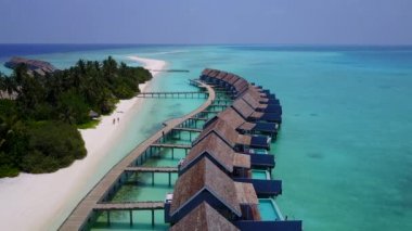 Rahatlatıcı tatil köyünün insansız hava aracı görüntüsü beyaz kum arka planına sahip berrak su tarafından kırılıyor