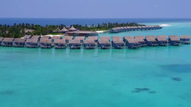 Gökyüzü insansız hava aracı beyaz kumlu arka planlı, mavi deniz kenarında tatil yapıyor.