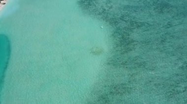 Mavi okyanus ve beyaz kum arka planındaki rahatlatıcı körfez sahili manzarası.