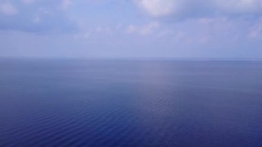 Lüks sahil şeridinin sığ okyanus manzaralı ve temiz kum arka planlı insansız hava aracı görüntüsü.