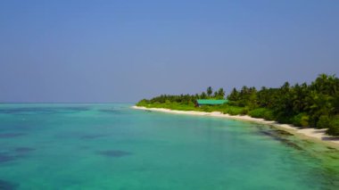 Tropikal adanın hava aracı panoraması sığ deniz ve beyaz kum arka planıyla yıkılıyor.