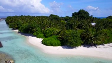 Beyaz kum zeminli sığ bir lagünün kıyısında cennet gibi bir adanın havadan yolculuğu.
