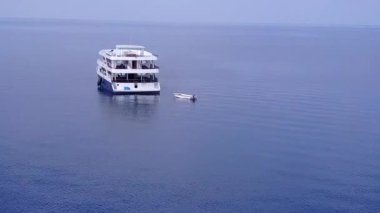 Mavi su ve beyaz kum arka planında sakin deniz kıyısı tatili havası.