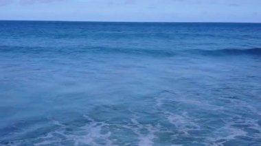 Mavi okyanus kıyısında beyaz kumlu arka planda mükemmel tatil yeri manzarası.