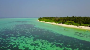 Cennet sahil şeridinin mavi okyanus ve beyaz kum arka planındaki insansız hava aracı sahnesi.