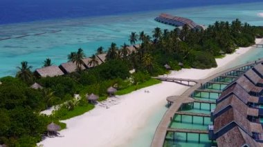 Mavi deniz kıyısında beyaz kumlu arka planda tropikal sahil turizmi.