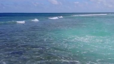 Mavi yeşil lagünün yanında, beyaz kum arka planlı sakin sahil saatinin insansız hava aracı deniz manzarası.