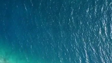 Pürüzsüz su ve beyaz kumlu arka planda huzurlu sahil saatinin insansız hava aracı soyutlaması