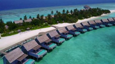 Lüks lagünün hava aracı sahili beyaz kum arka planıyla berrak denizi yarıp geçiyor.