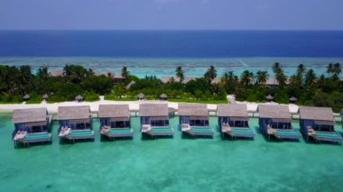 İnsansız hava aracı görüntüsü turkuaz okyanus ve beyaz kumlu arka planla sakin sahil macerası.