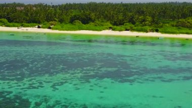Lüks lagünün insansız hava aracı turizmi beyaz kum arka planıyla mavi deniz kıyısında kırılıyor.