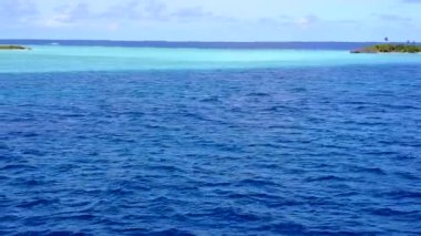 Deniz kıyısının güneşli deniz manzarası, mavi yeşil okyanus ve beyaz kumlu arka plan güneş ışığı.