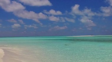 Huzurlu sahil gezisinin güneşli manzarası. Mavi lagünün yanında, tatil köyünün yakınındaki beyaz kum arka planında.