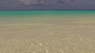 Huzurlu turistik plaj manzarası. Su mavisi okyanus kıyısında tatil köyü yakınlarında beyaz kum arka planlı.