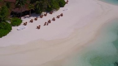 Turkuaz okyanus ve resifin yakınındaki beyaz kum arka planıyla deniz turizminin güneşli manzarası.