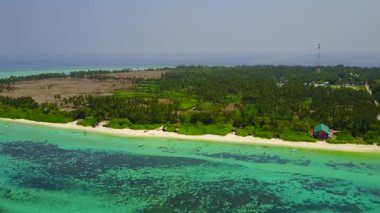 Mavi okyanus ve beyaz kumlu arka planda rahatlatıcı turistik plaj seyahatinin insansız hava aracı görüntüsü