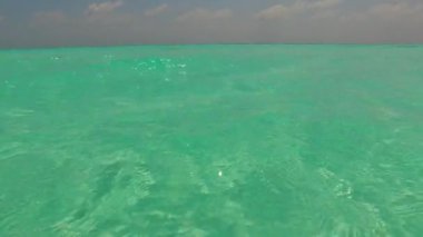 Geniş açı manzaralı cennet adası sahili. Mavi deniz kıyısında, dalgaların yanında beyaz kumlu arka planda.