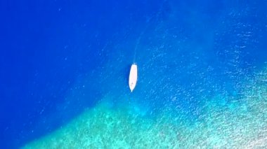 Mavi okyanus kıyısındaki egzotik sahil yolculuğunun güneşli dokusu ve güneş ışığında beyaz kum arka planı.