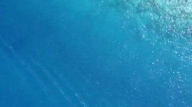 Sakin tatil beldesinin yaz doğası. Mavi deniz kıyısında, beyaz kumlu arka planda güneş ışığı altında.