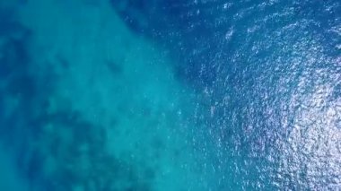 Su mavi suyu ve tatil köyü yakınlarındaki parlak kum arka planındaki güzel sahil yolculuğunun gündüz soyutlanması.