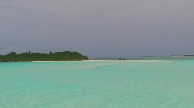 Deniz turisti plajının güneşli doğası resifin yakınındaki açık kumdan oluşan mavi göl kıyısında kırılıyor.