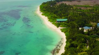 Tropikal lagünün hava manzarası beyaz kumlu arka planlı mavi okyanus tarafından kırılıyor.