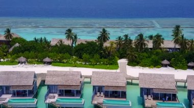 Güneşli gökyüzü cennet gibi kumsalda, mavi yeşil lagünün kıyısında tatil köyü yakınlarında beyaz kumlu arka planda.