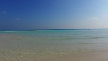 Turkuaz okyanus ve palmiyelerin yakınındaki beyaz kumlu arka plandan oluşan mükemmel ada sahil saatinin gündüz doğası.