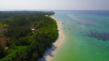 Turkuaz deniz kıyısında dalgalara yakın beyaz kum arka planında güneşli bir sahil gezisi.