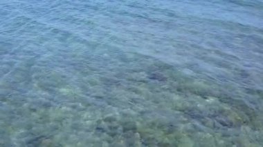 Gün batımından önce beyaz kum arka planlı mavi okyanus kıyısındaki deniz turistlerinin boş soyutlamaları.