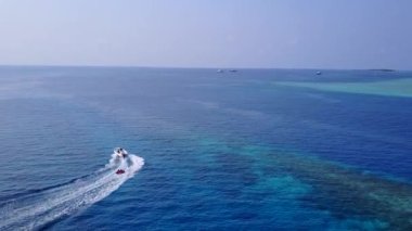 Turkuaz okyanus ve dalgaların yakınındaki beyaz kumlu arka plandan oluşan rahatlatıcı körfez sahil gezisi.