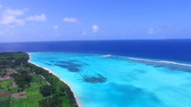 Mavi deniz kıyısındaki tropikal turist plajı ve resifin yakınındaki parlak kumsal manzarası geniş açılı.