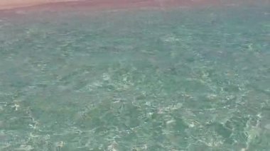 Mavi okyanus ve resifin yakınındaki beyaz kumlu arka planda güneşli sakin ada plaj tatili