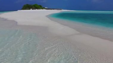 Şeffaf su ve kumsalın yakınındaki parlak kumlu arka planda cennet gibi turistik sahil seyahatinin güneşli deniz manzarası.