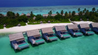 Lüks turist plaj gezisinin güneşli deniz manzarası berrak su kenarında beyaz kumlu arka planda sörfün yanında