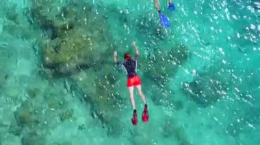 Şeffaf sularda, dalgalara yakın temiz kum arka planında tropikal sahil şeridinde güneşli turizm