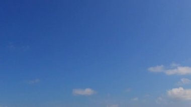 Lüks sahil plajının boş manzarası kumsalın yakınındaki beyaz kum arka planıyla mavi sulardan kırılıyor.