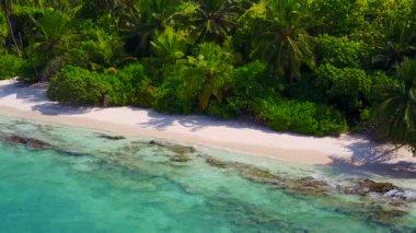 Turkuaz okyanusun kumsala yakın beyaz kumlu arka planlı güneşli turistik plaj tatili