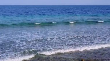 Turkuaz deniz ve tatil köyü yakınlarındaki beyaz kumlu arka planda rahatlatıcı sahil gezisi manzarası