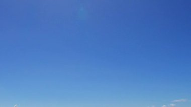 Günbatımından önce beyaz kum arka planlı, mavi okyanus kıyısındaki mükemmel deniz kıyısı gezisinin soyut bir örneği.