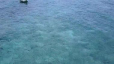 Mavi okyanus kıyısında güneşli bir sahil manzarası ve kumsal kenarında beyaz kum arka planı.