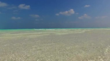 Mavi su kıyısında dinlendirici sahil tatili manzarası ve kumsalın yakınındaki beyaz kumlu arka plan.