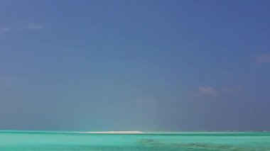 Su mavisi okyanusu ve beyaz kum arka planının güneş ışığı altında oluşturduğu egzotik turist plajı manzarası.