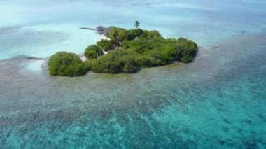 Sükunet koyu kumsalının güneşli gökyüzü, kumsalın yakınındaki beyaz kum arka planına sahip mavi yeşil lagünün yanında.