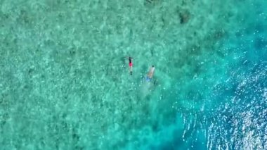 Mükemmel sahil şeridinin sıcak turizmi, resifin yakınındaki beyaz kumlu arka planda mavi sulardan kırılıyor.