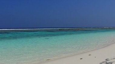 Güneş ışığı altında temiz kumlu arka plana sahip, su mavisi bir okyanusun kenarındaki tropikal lagün plajı yaşam tarzının soyutlamasını kapat.