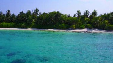 Mavi yeşil okyanus ve dalgalara yakın beyaz kumlu arka planda boş bir sahil manzarası.