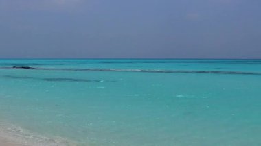 Lüks turist plajlarının mavi denizi aşan manzarası ve dalgaların yakınındaki temiz kum arka planı.