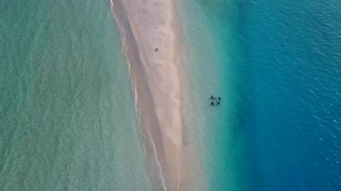 Cennet sahili boş sahili, kumsalın yakınındaki beyaz kum arka planıyla şeffaf denizi aşıyor.