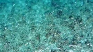 Cennet adasının boş deniz manzarası. Mavi yeşil lagün ve dalgaların yakınında beyaz kumlu arka plan.
